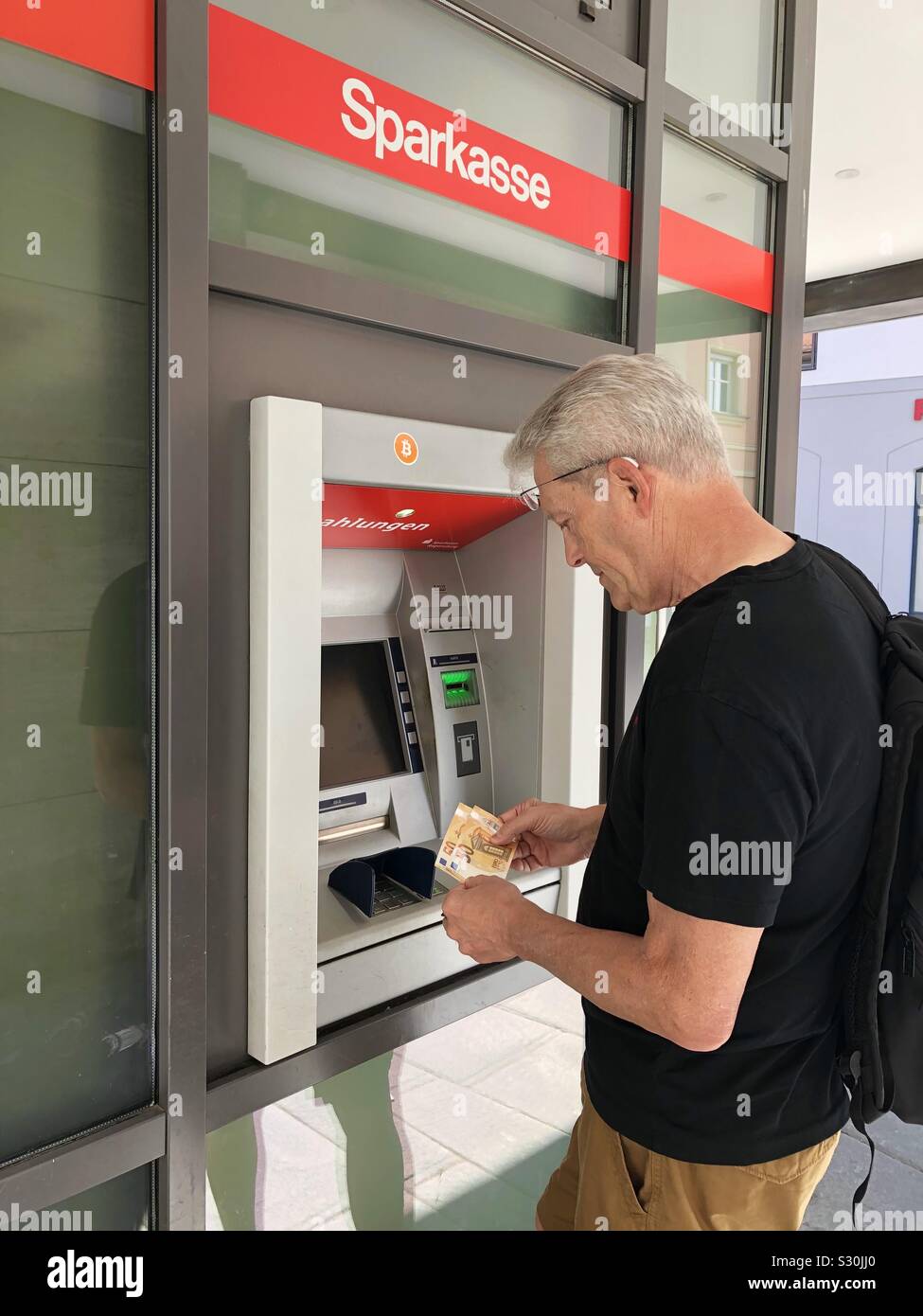Mann an Geldautomaten Maschine in Regensburg, Deutschland, Bayern. Model Released. - Smartphone-aufgenommenes Stockfoto