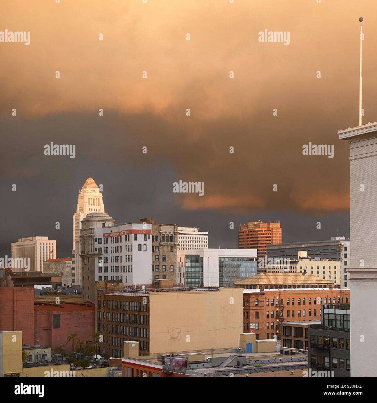 LOS ANGELES, Ca, DEZ 2019: Skyline der Innenstadt mit dem Rathaus im Hintergrund, leuchtet orange durch dramatische Wolken bei Sonnenuntergang Stockfoto