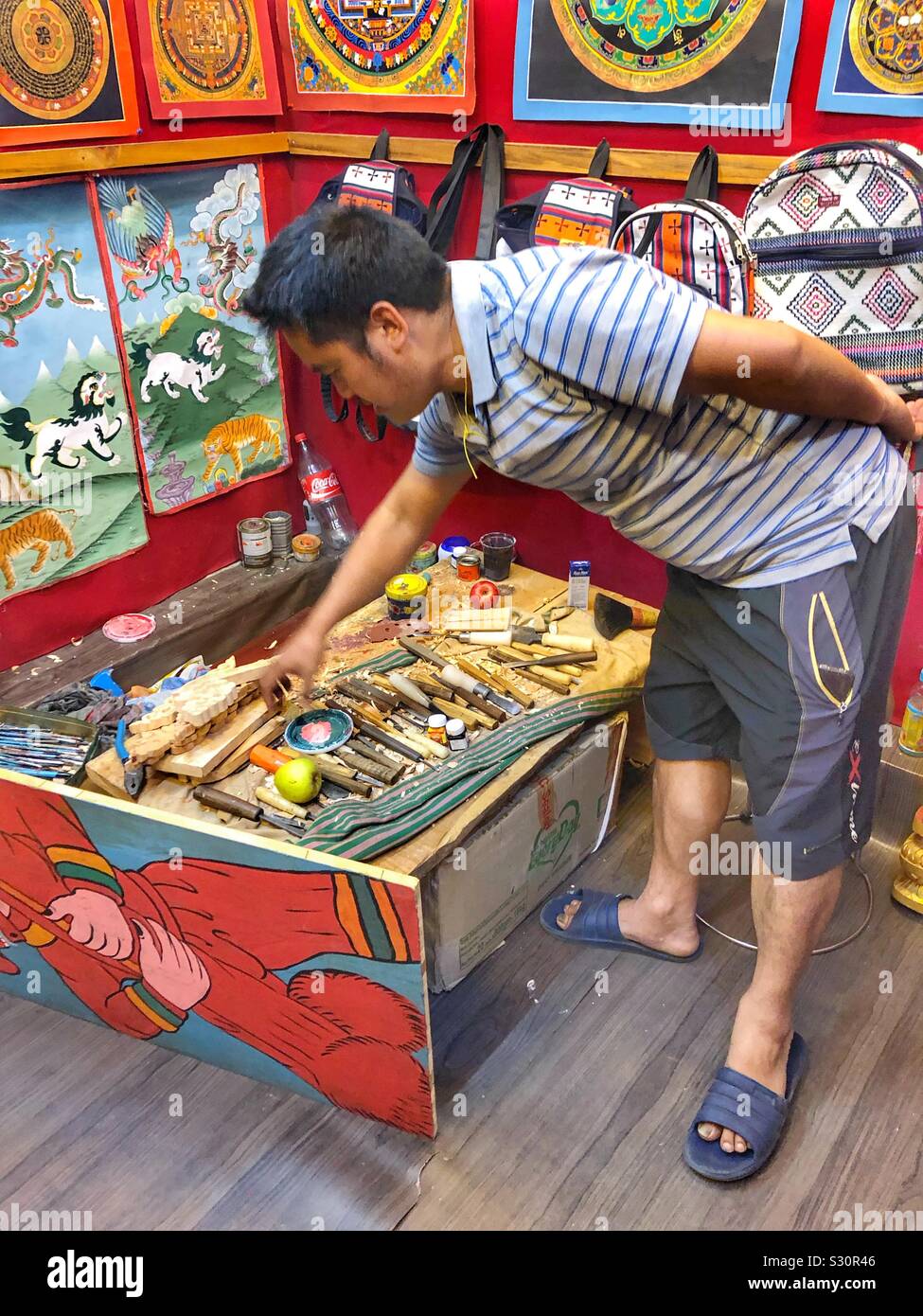 Handwerker zeigt seine Schnitzwerkzeuge in Bhutan. - Smartphone-aufgenommenes Stockfoto