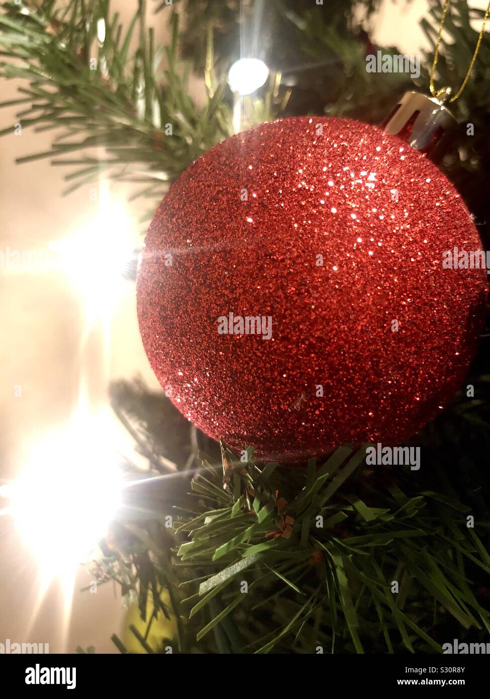 Rot glitzernde Weihnachten Ornament auf einem Baum mit Licht. Stockfoto