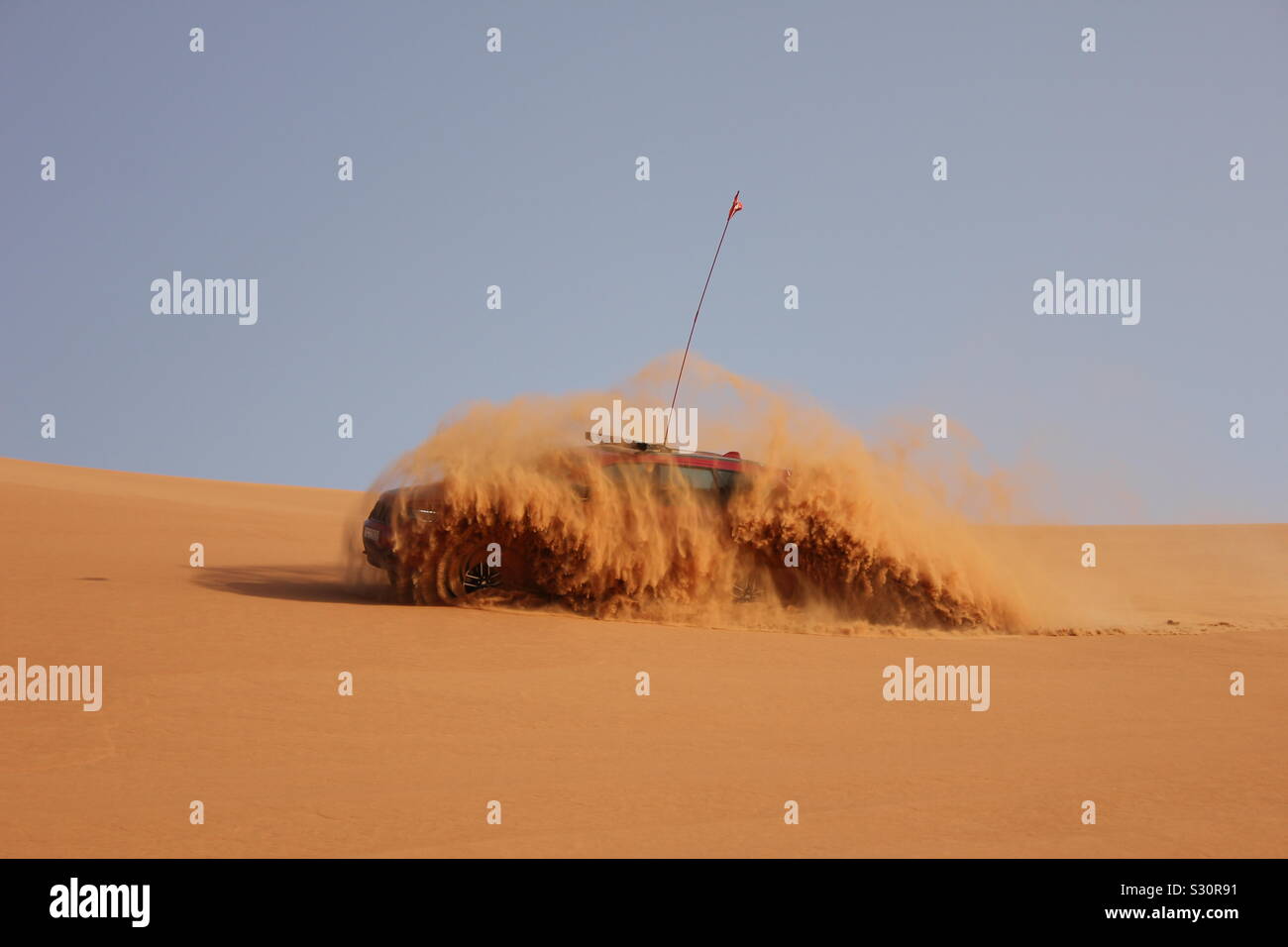Ein Jeep Grand Cherokee Butterfässer, eine Dusche, während durch die Wüste Sand Dünen in Dubai, Vereinigte Arabische Emirate angetrieben wird. Stockfoto