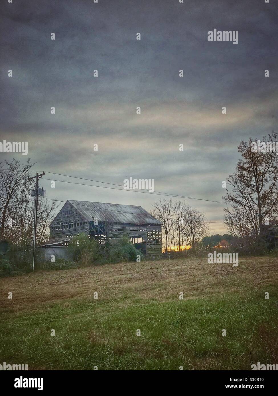 Verwitterte alte Scheune mit Dezember Sonnenuntergang Stockfoto