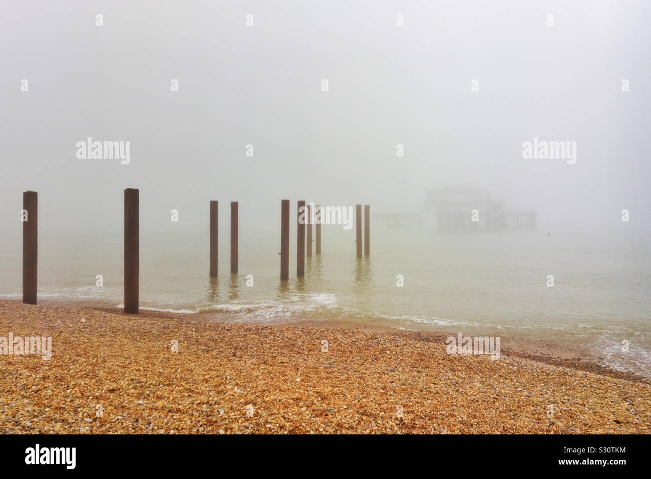 Die Überreste des West Pier in Brighton, East Sussex, England, Großbritannien, sind nur durch den frühen Morgennebel sichtbar. - Smartphone-aufgenommenes Stockfoto