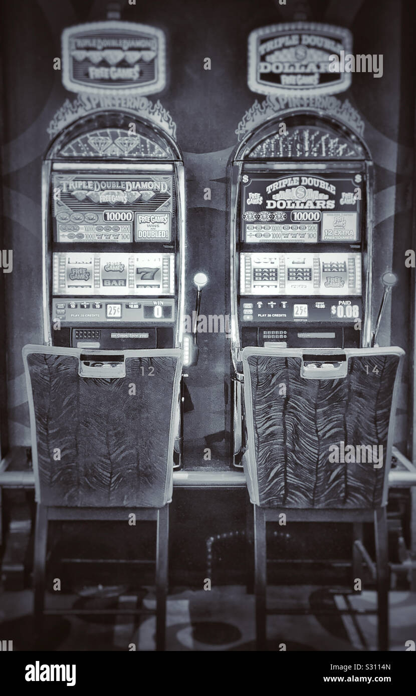 Zwei leere Stühle vor Spielautomaten im Casino nummeriert 12. und 14. Stockfoto