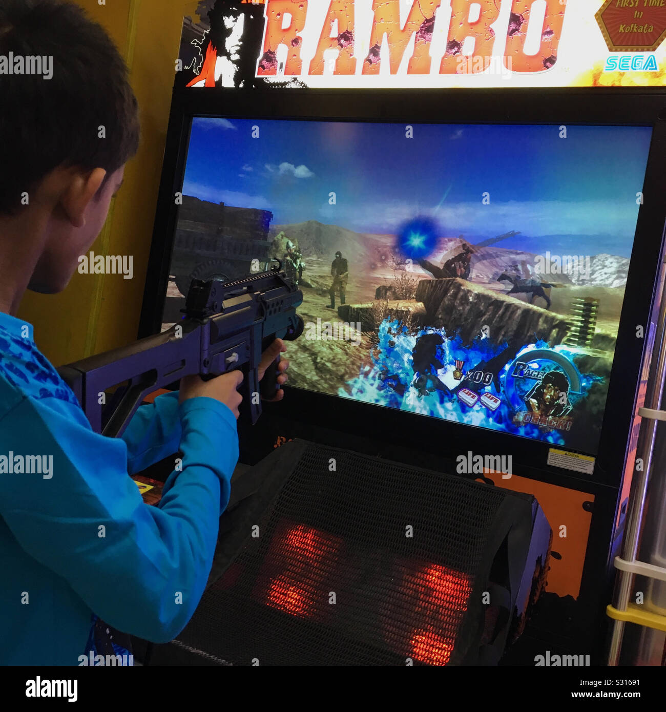 Junge in Kolkata, Indien ist ein Rambo video game in eine Spielhalle. Stockfoto