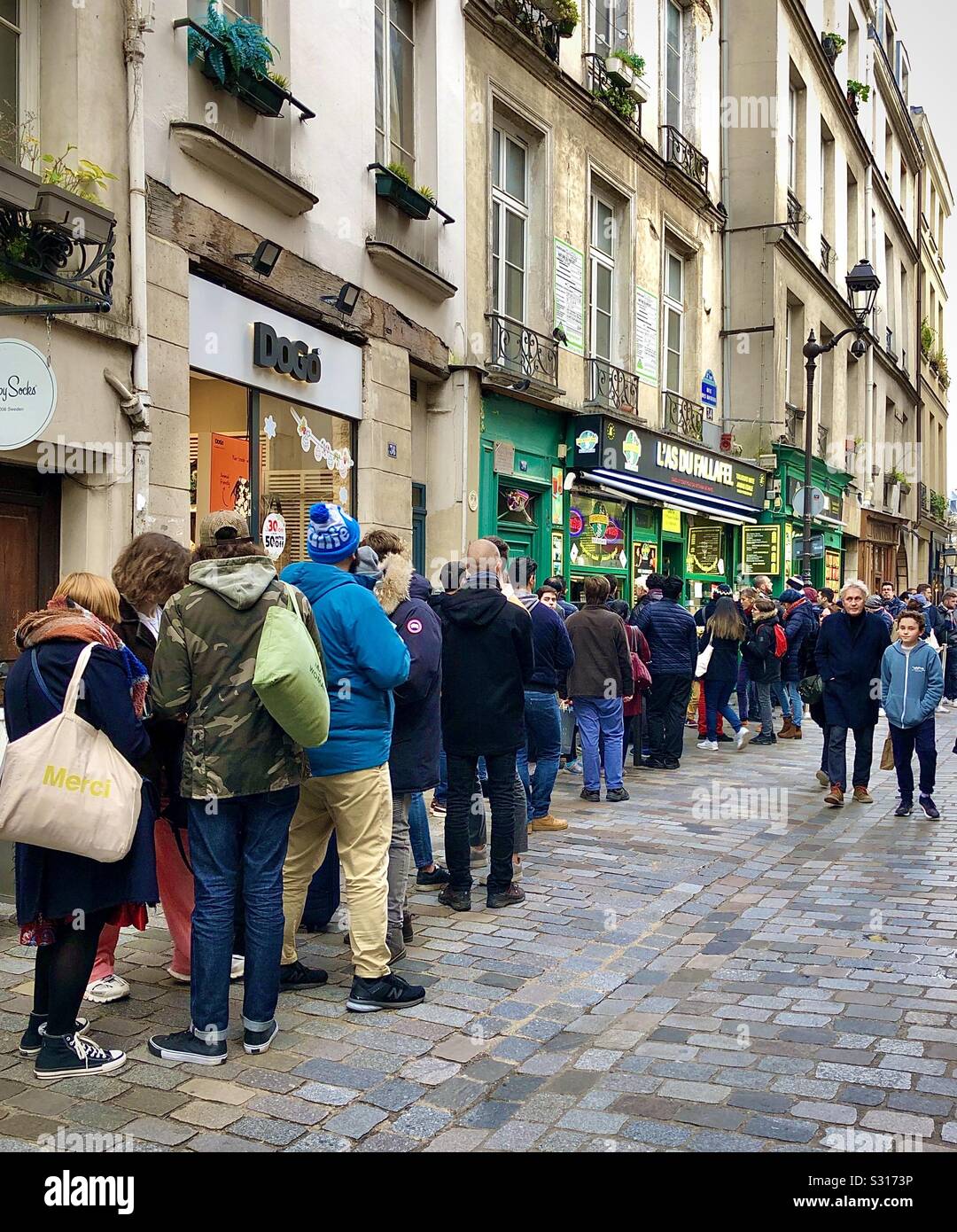 Traditionelle Schlange von hungrigen Kunden außerhalb "L'Wie du Fallafel" Restaurant in Le Marais, Paris, Frankreich. - Smartphone-aufgenommenes Stockfoto