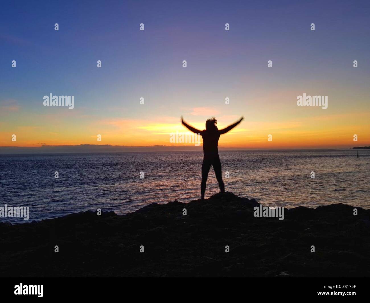 Junge Frau tun Star springt an der Küste bei Sonnenuntergang Stockfoto