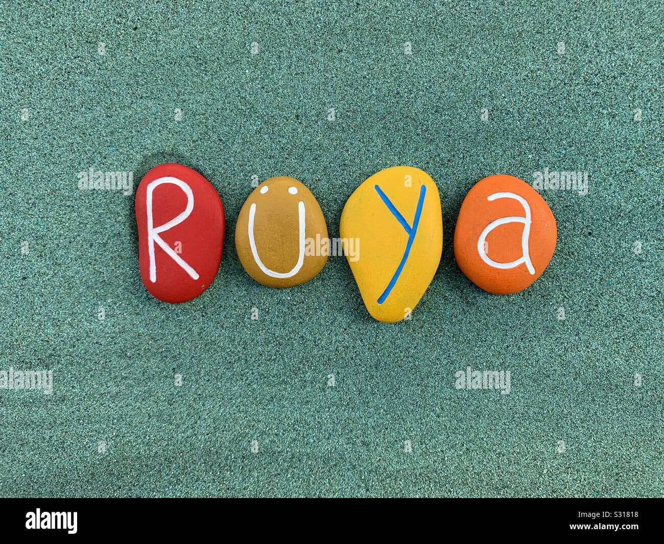 Rüya, türkische Vornamen komponiert mit farbigen Stein Briefe über grünen Sand Stockfoto