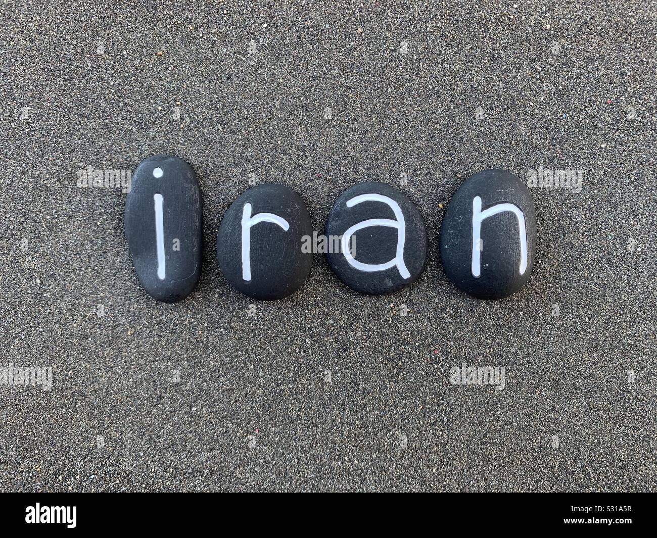 Iran, Islamische Republik Iran, Souvenir mit besteht aus schwarzen Stein Briefe über schwarzen vulkanischen Sand - Smartphone-aufgenommenes Stockfoto