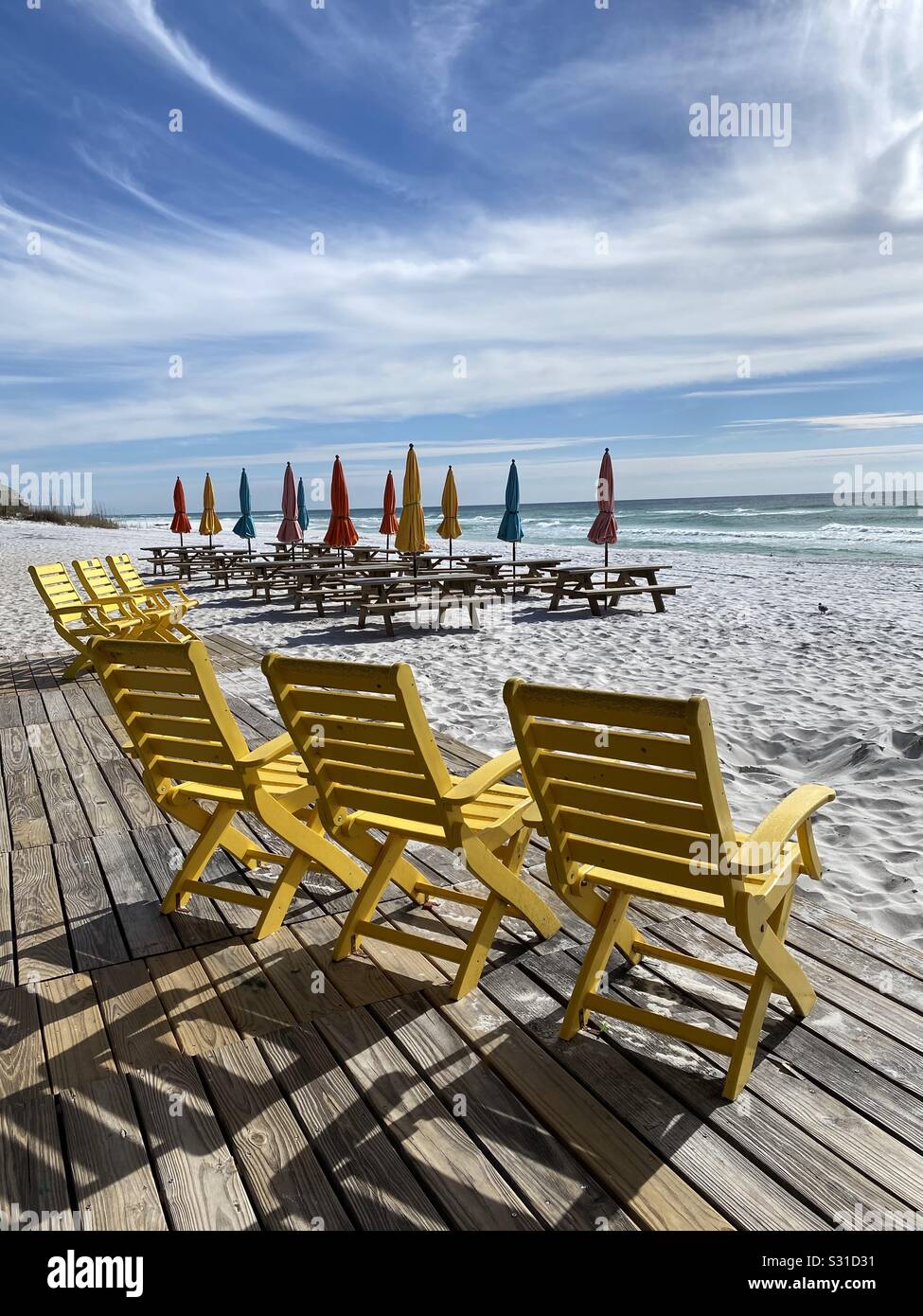 Sitzplatz im Freien am weißen Sandstrand mit bunten Stühlen, Picknickbänken und Sonnenschirmen Stockfoto