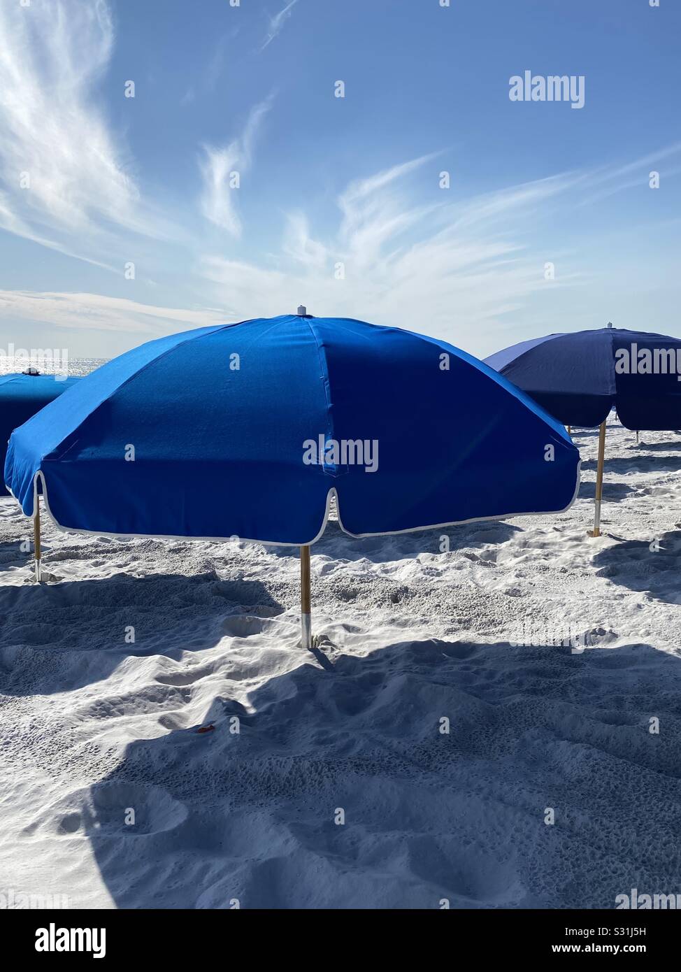 Tiefblaue Sonnenschirme am weißen Strand mit tiefblauem Himmel Stockfoto