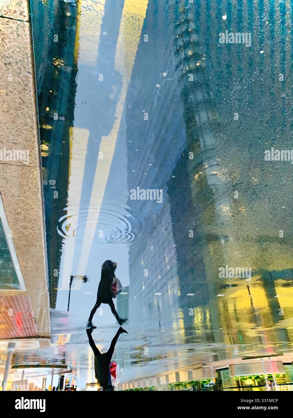 Silhouette der Frau, die im Regen mit zweigelben Linien spazieren geht Stockfoto