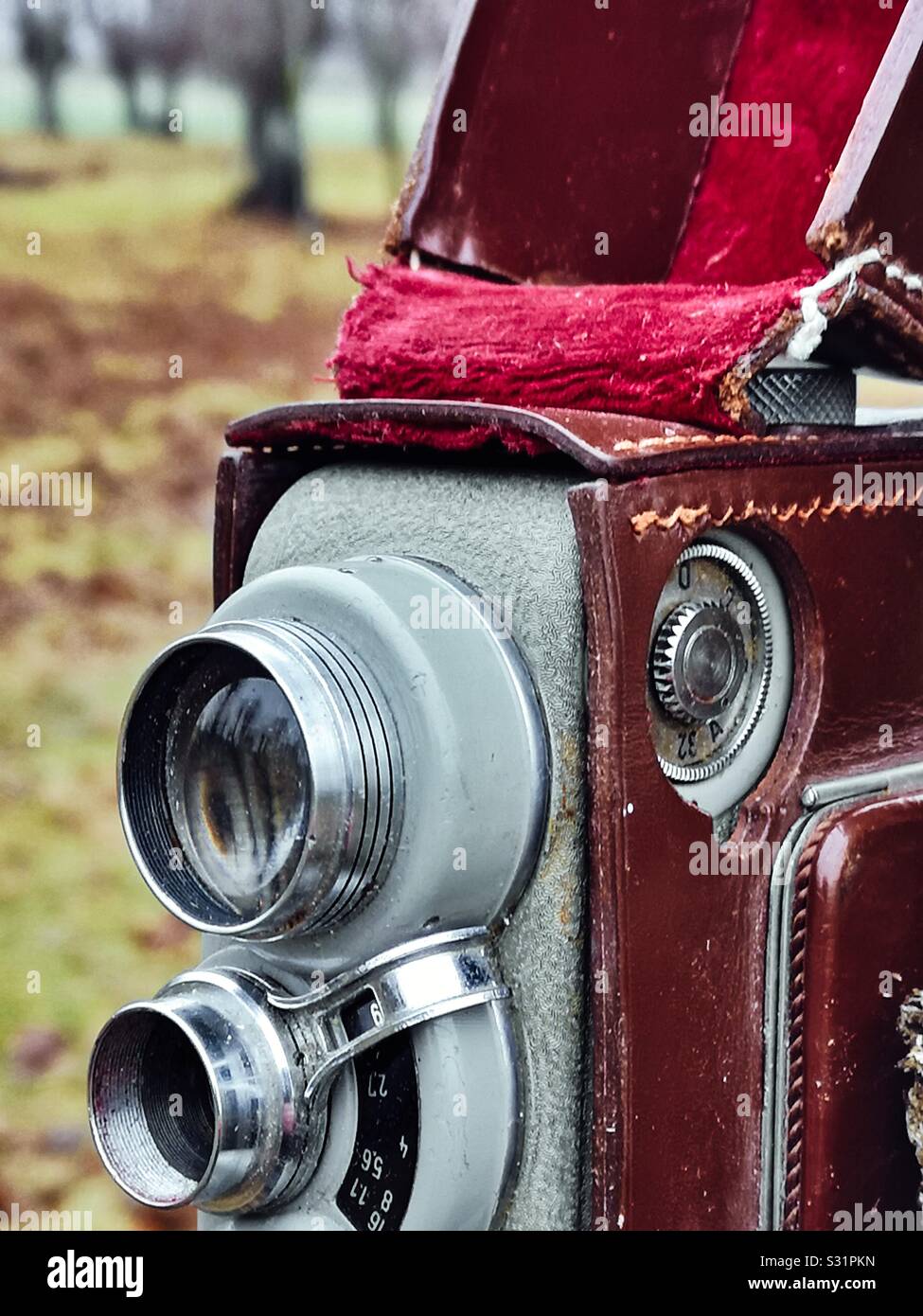 Nahaufnahme der Retro-Vintage-Filmkamera in roter, samengefütterter Ledertasche im Freien Stockfoto