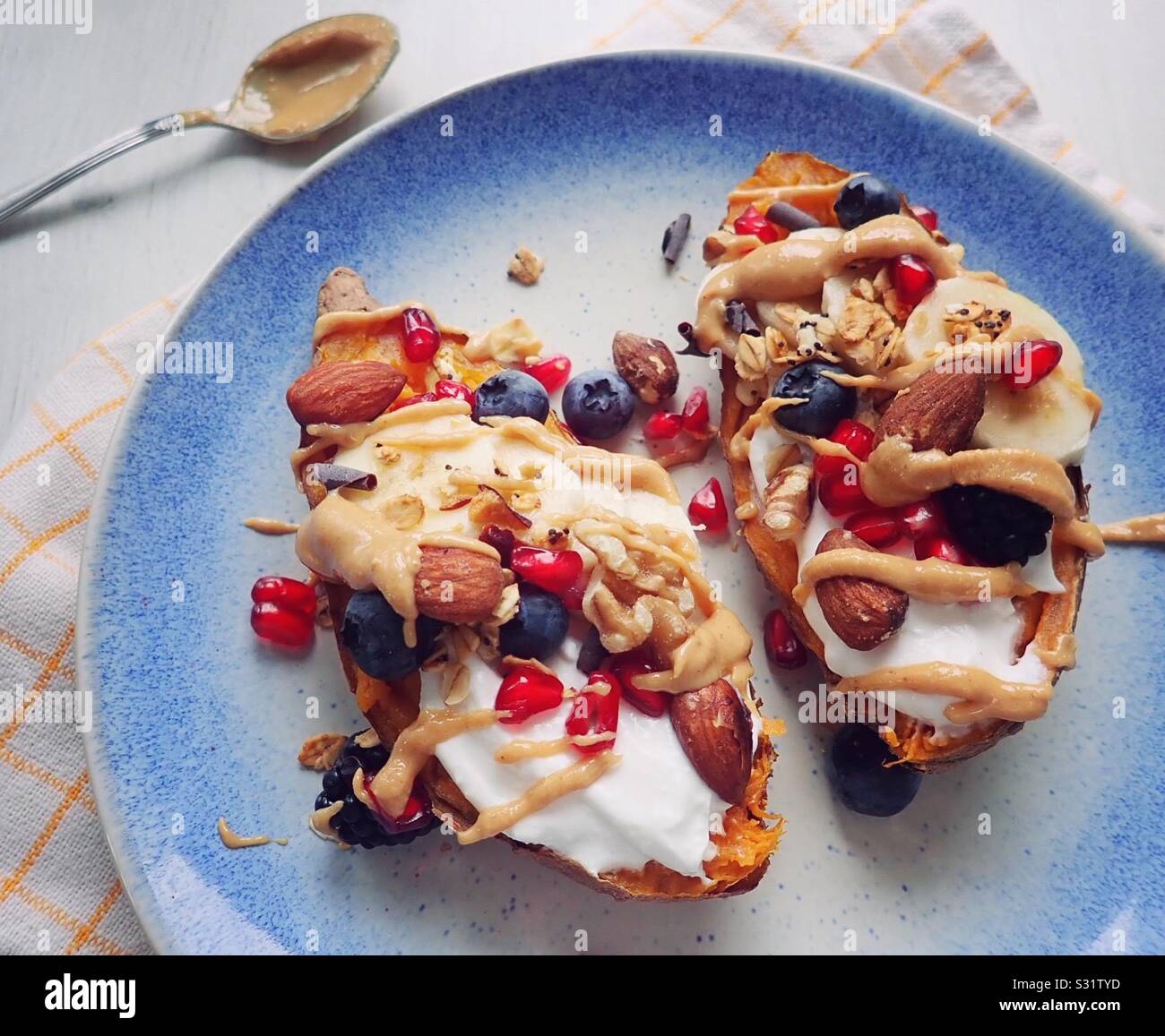 Süsse Kartoffeln gebacken mit Joghurt, Müsli und Erdnussbutter. Perfekte gesundes Frühstück! Stockfoto