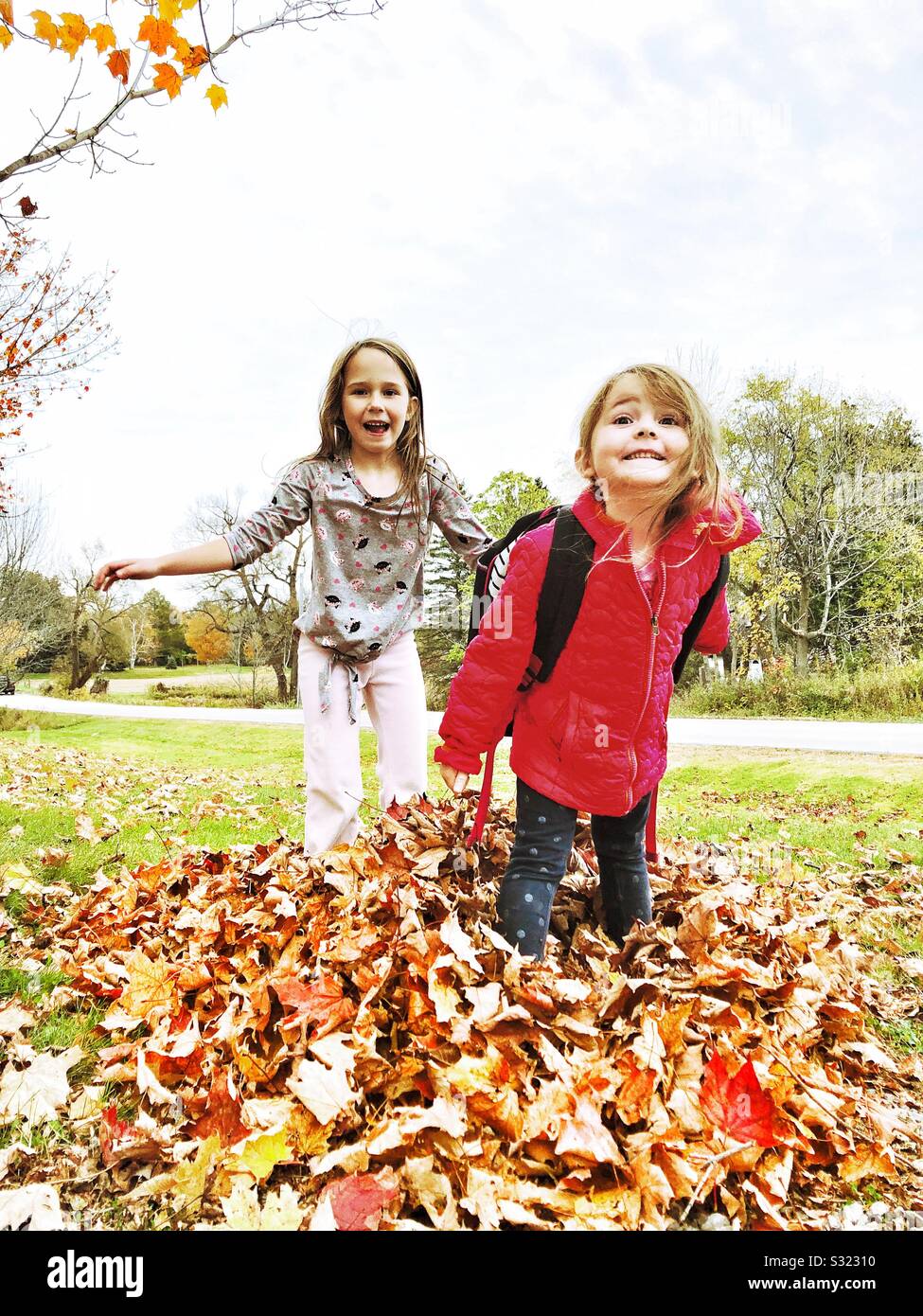 Zwei junge Mädchen, die im Herbst Blätter Stockfoto