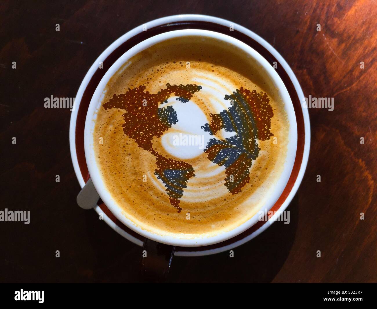 Die Welt des Kaffees in einer Tasse perfekten Cappuccino. Blick von oben. . Konzept – Quelle/Objekt, Symbol, Perfektion, Miniatur. Aromatisch. Wo es herkommt. Stilvoll. Stilisiert. - Smartphone-aufgenommenes Stockfoto