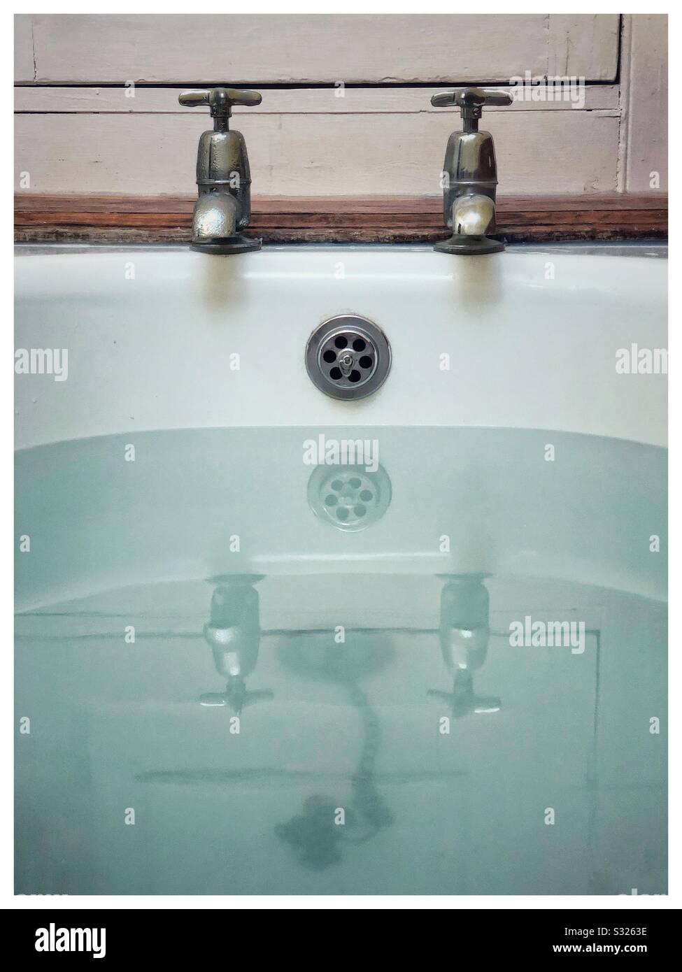 Alte Wasserhähne, die sich in der Badewanne widerspiegeln Stockfoto