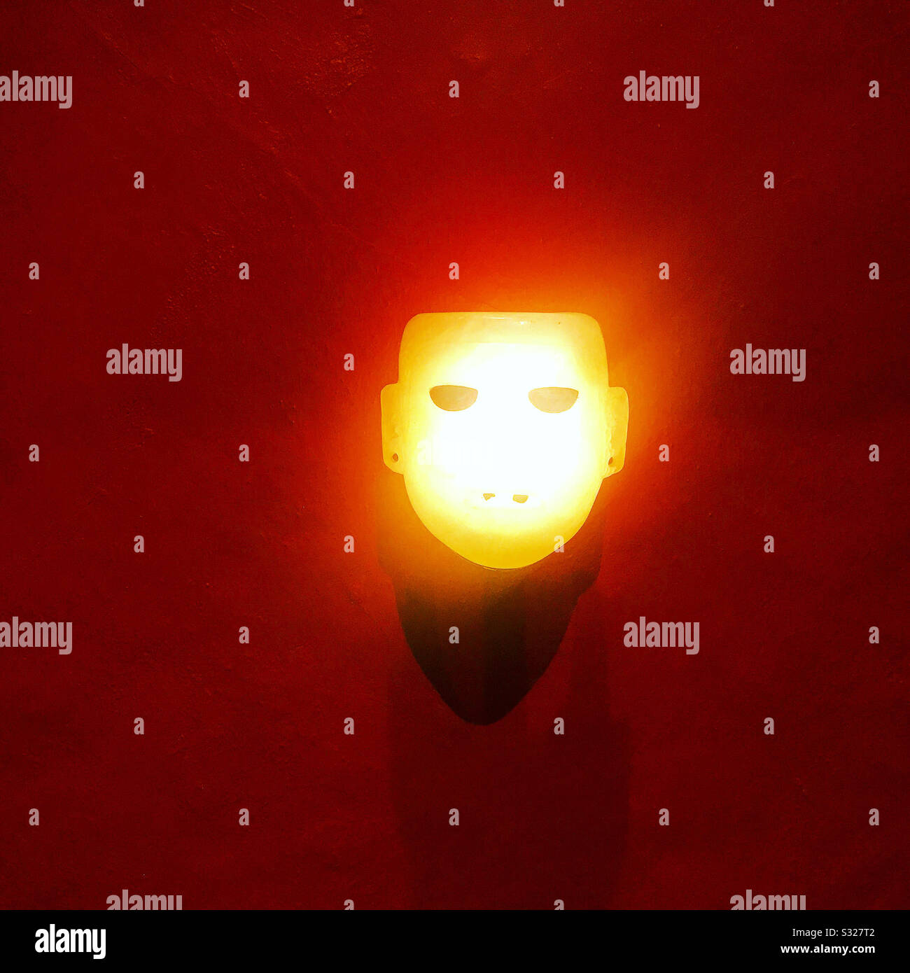 Eine von einer elektrischen Glühlampe beleuchtete Steinmaske wird im Templo Mayor Museum in Mexiko-Stadt ausgestellt Stockfoto