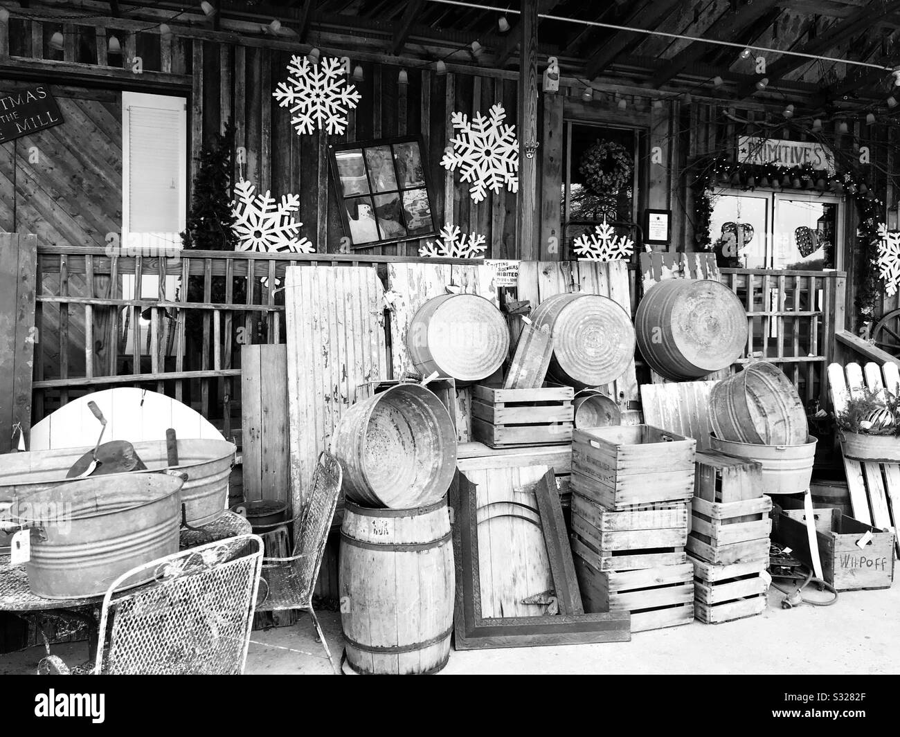 Sammlung von Holzkisten und Fässern vor Antiquitätengeschäften in Schwarzweiß. Stockfoto