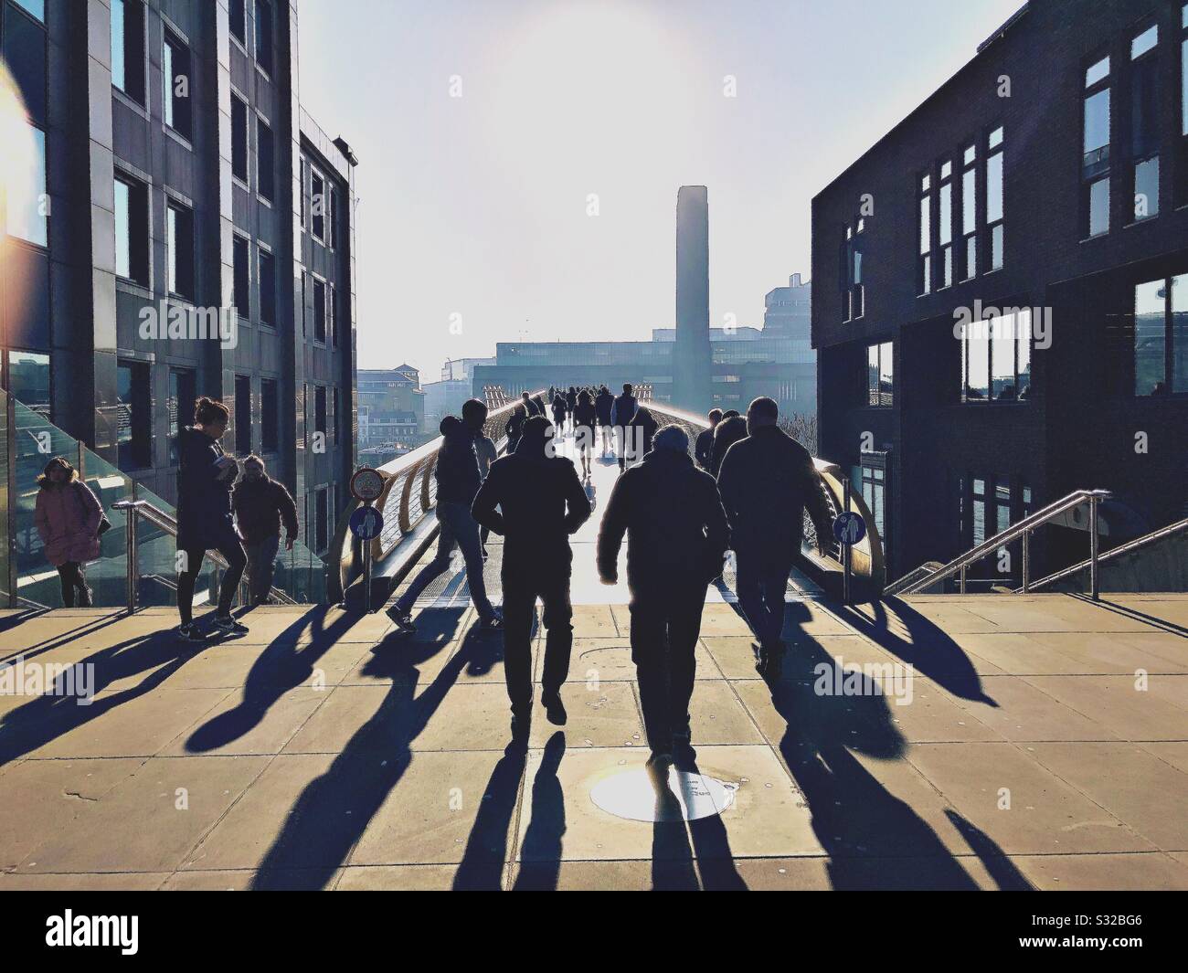 Mittagswanderung über die Millennium Bridge, London bei Sonnenschein im Winter. Stockfoto