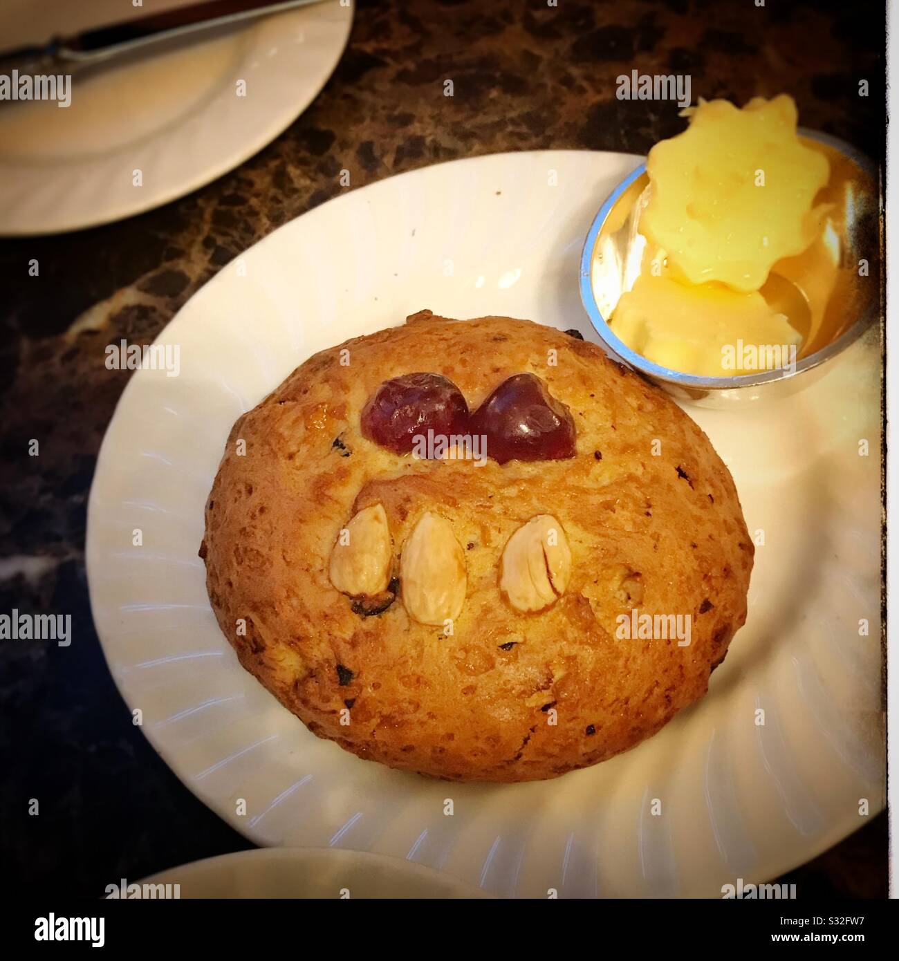 Fetter Rascal Scone auf einem Teller mit Butter Stockfoto