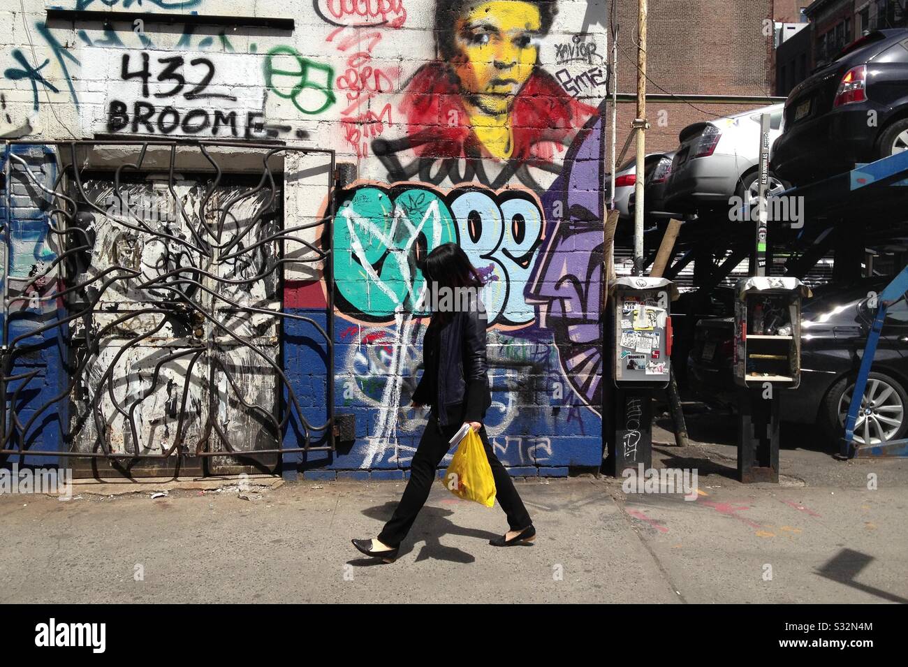 Frau, die vor Graffiti in der Broome Street, New York City, spazieren geht Stockfoto