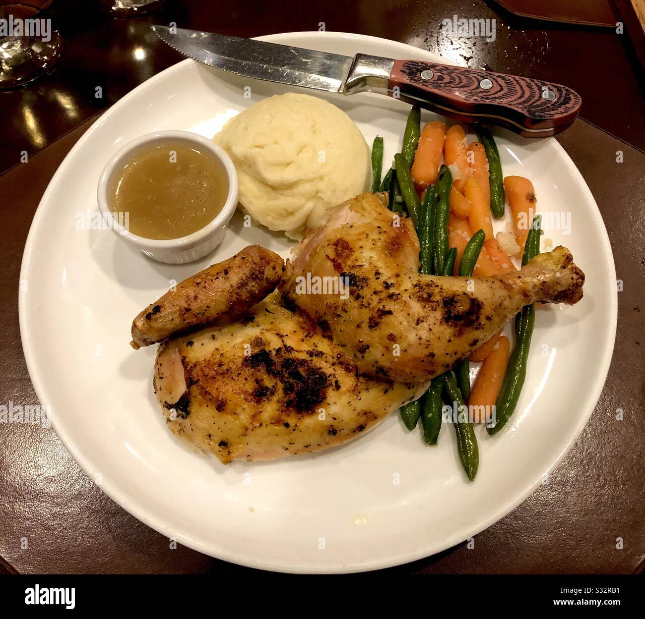 Platte aus gebackenem Huhn, Kartoffelpüree, Soße und Gemüse. - Smartphone-aufgenommenes Stockfoto