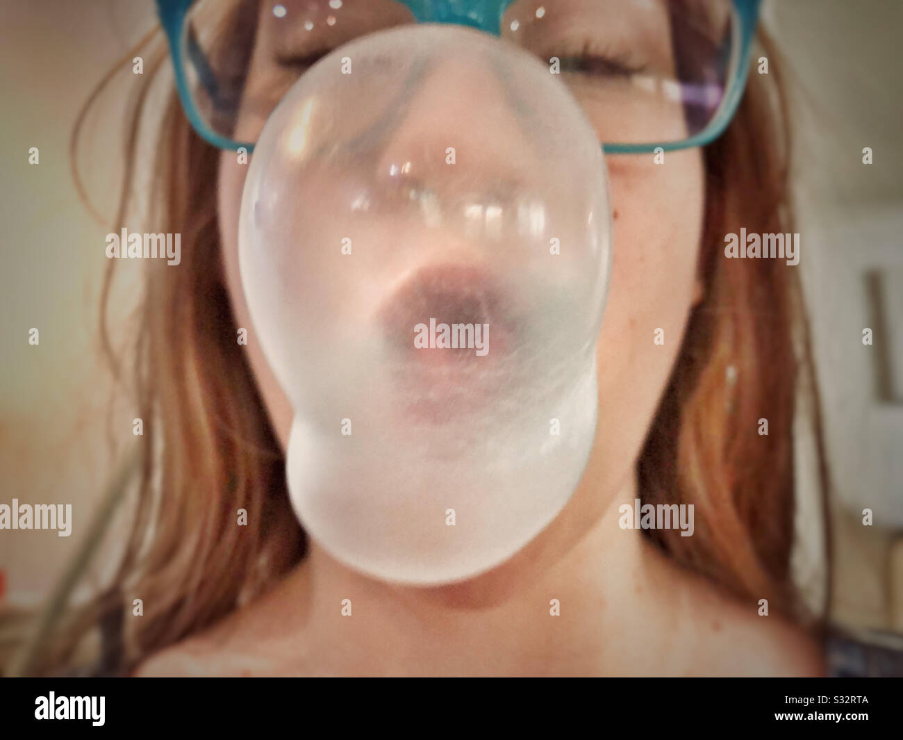 Mädchen bläst ein Bubblegum. - Smartphone-aufgenommenes Stockfoto