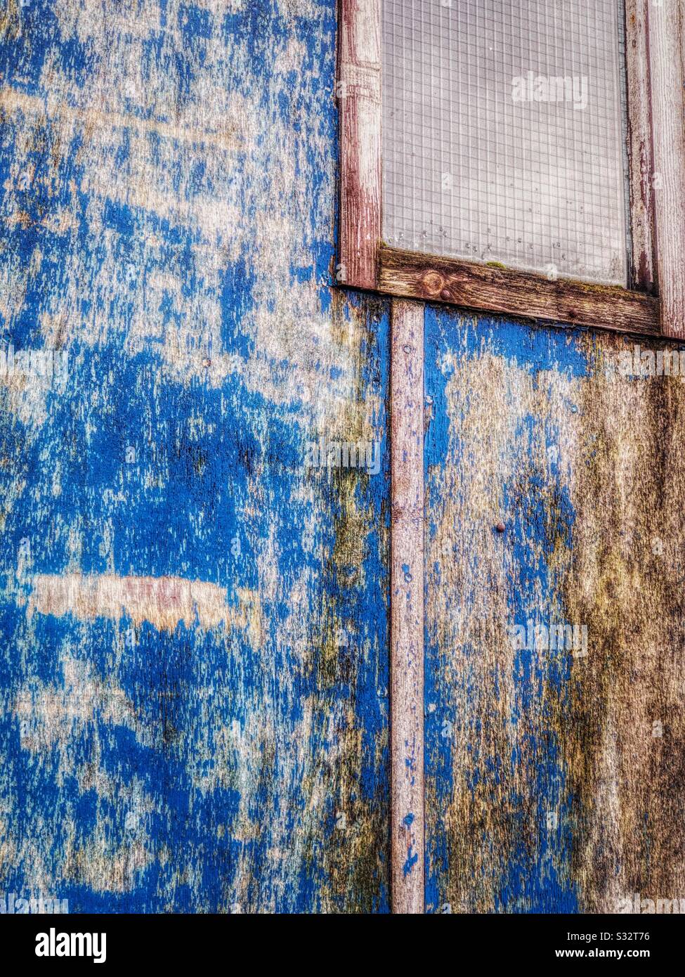 Verfallende Lackierungen an alter Holzwand, mit Fenster. Stockfoto