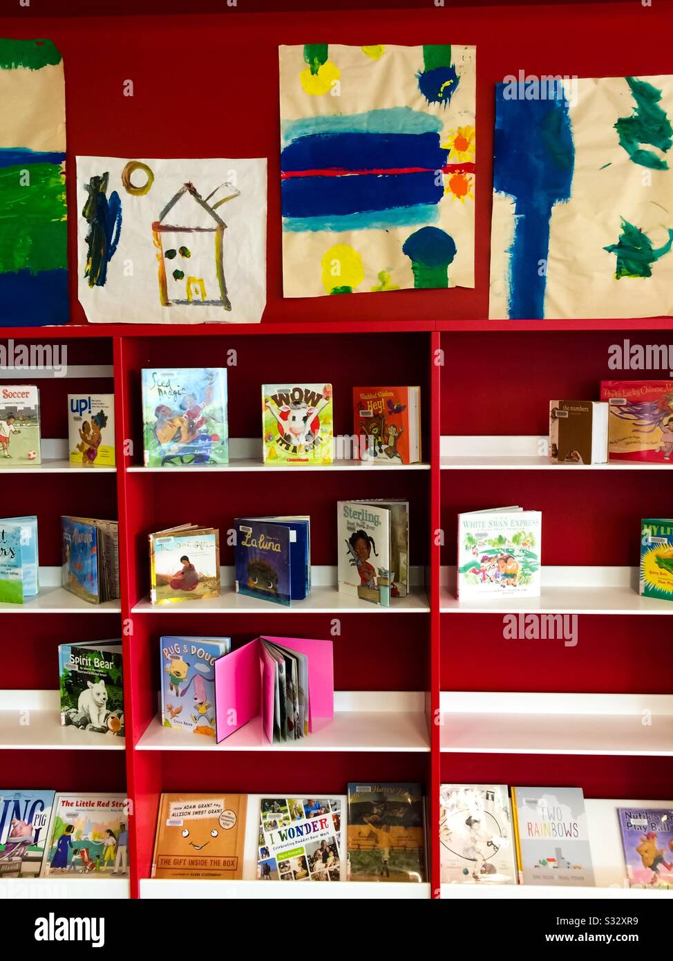 Kinderbücher und Kinderkunst sind ausgestellt. Eine unschuldige Welt. Spontane primitive Gemälde. - Smartphone-aufgenommenes Stockfoto