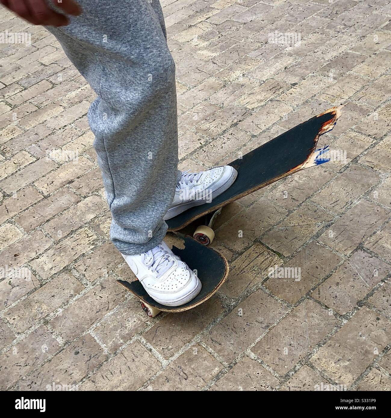Teenager mit seinem kaputten Skateboard. Stockfoto