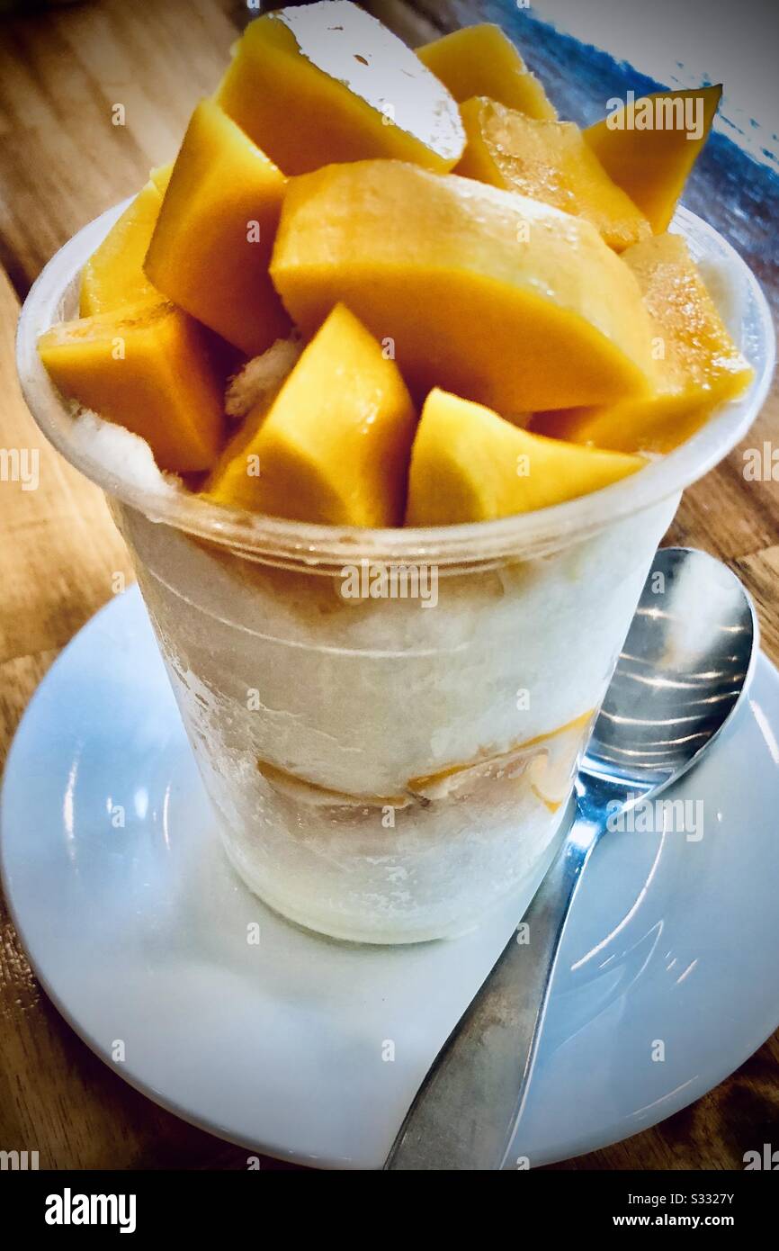 Bingsu (Koreanisch rasierte Eis) Tasse mit frisch geschnittenem Mango-Belag, serviert in Siem Reap, Kambodscha - Smartphone-aufgenommenes Stockfoto