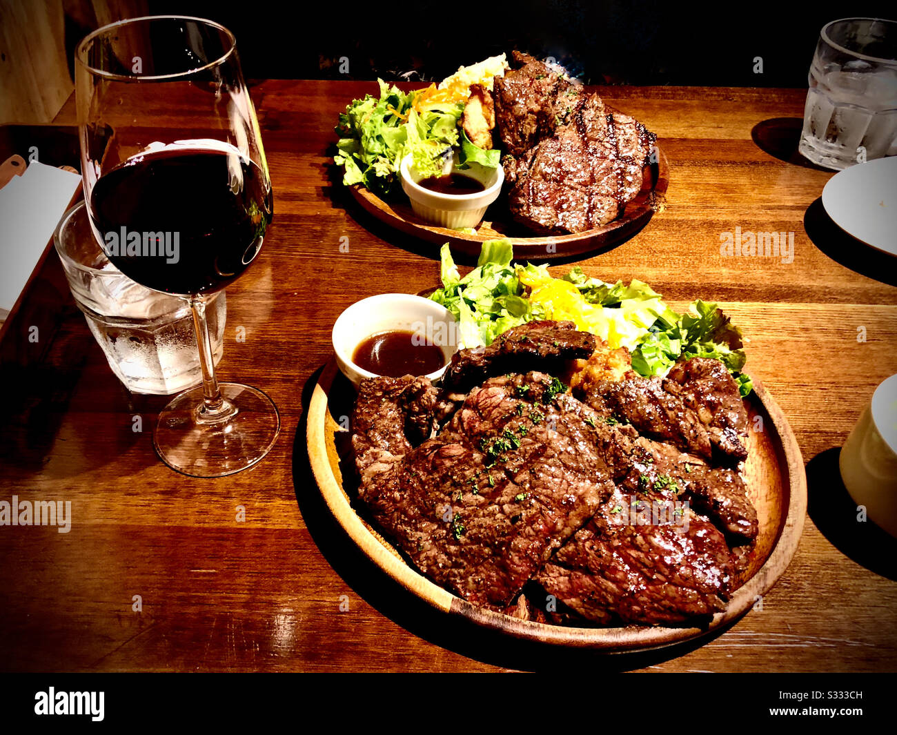 Steakabendessen für zwei Personen, mit Beissalat, Dressing und einem Glas Rotwein - Smartphone-aufgenommenes Stockfoto