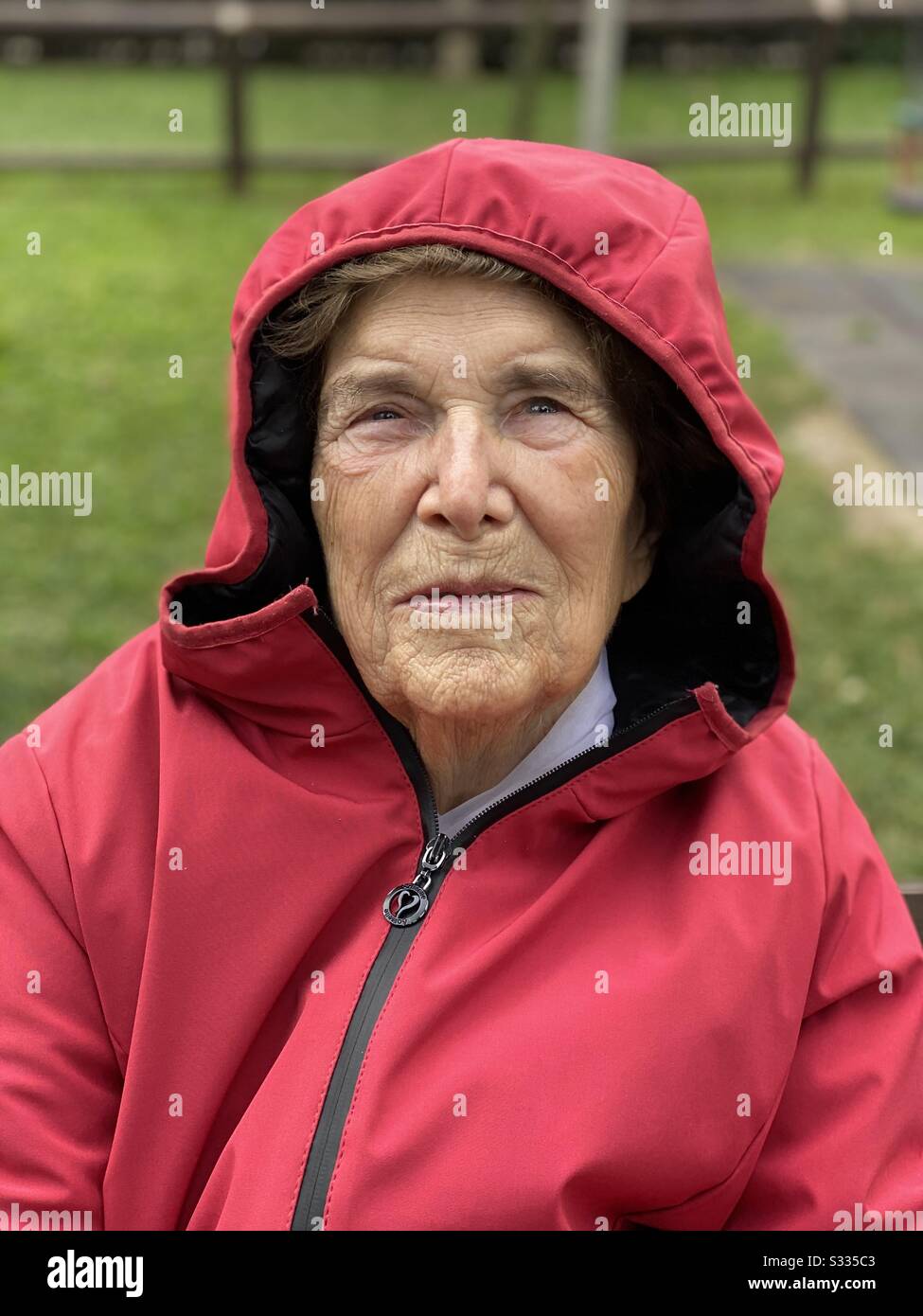 Nicht-agenisches Frauenporträt in einem öffentlichen Park rot gekleidet Stockfoto