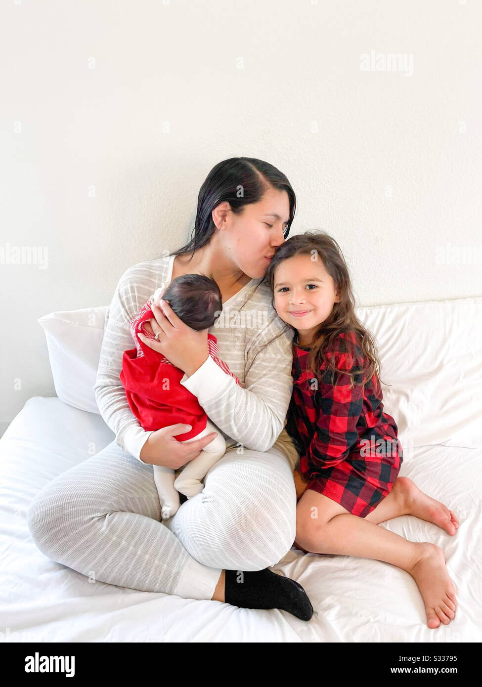Ein Momma, das an ihrem süßen Mädchen am Weihnachtsmorgen liebt Stockfoto