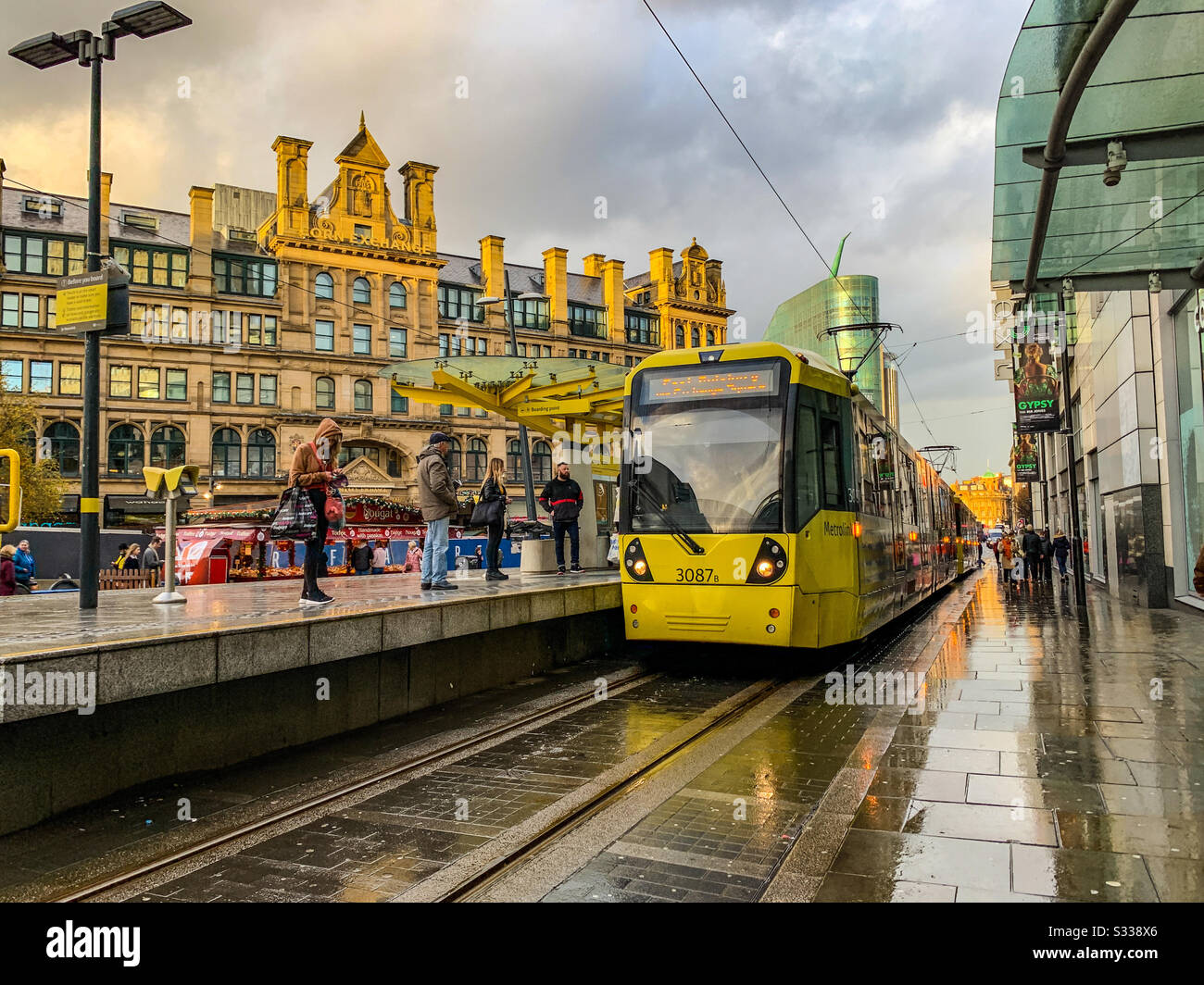 Metrolink-Tram, die an der Straßenbahnhaltestelle am Umsteigeplatz in Manchester ankommt Stockfoto