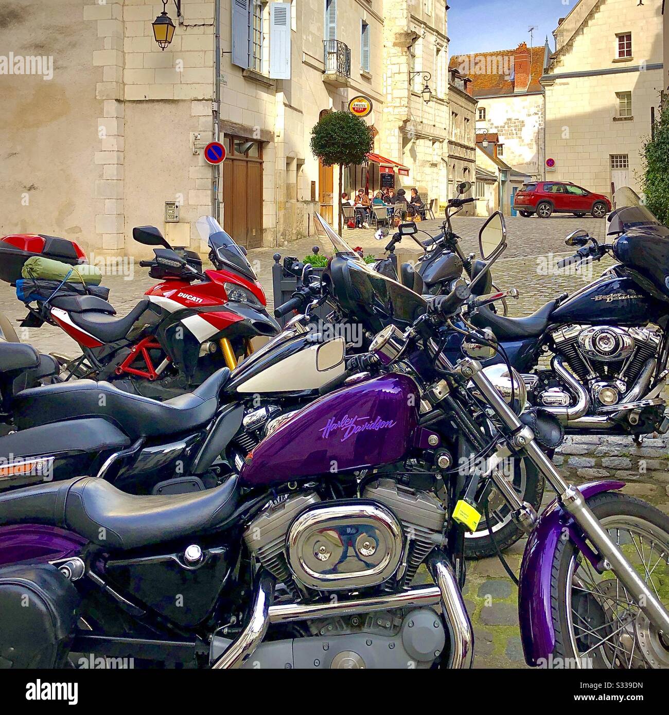 Motorräder auf dem alten Stadtplatz geparkt - Besitzer essen auf der Café-Terrasse - Loches, Indre-et-Loire, Frankreich. - Smartphone-aufgenommenes Stockfoto