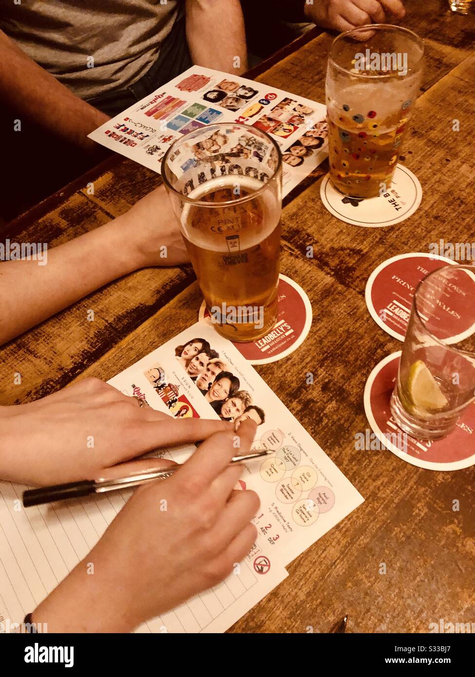 Nahaufnahme der Hand der Leute bei einem Pub-Quiz in London - Smartphone-aufgenommenes Stockfoto