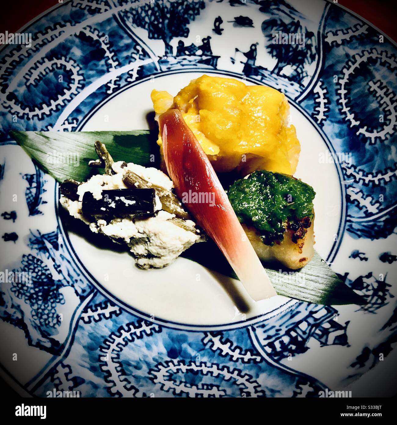 Nimono: Japanisches Gänseki-Gericht, gekochtes Gemüse und Fisch auf einem blauen Porzellangericht - Smartphone-aufgenommenes Stockfoto