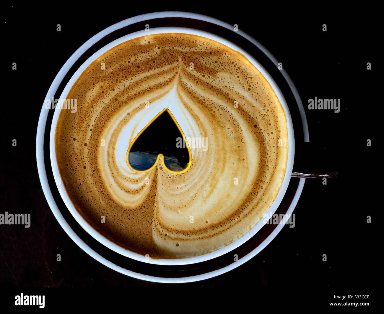 Das Herz des Kaffees. Eine Blattform in fließenden Linien, handgefertigt mit gedämpfter Milch, schwimmt um ein stilisiertes Herz. Ein gutes Beispiel für die Kunst des Barista Stockfoto