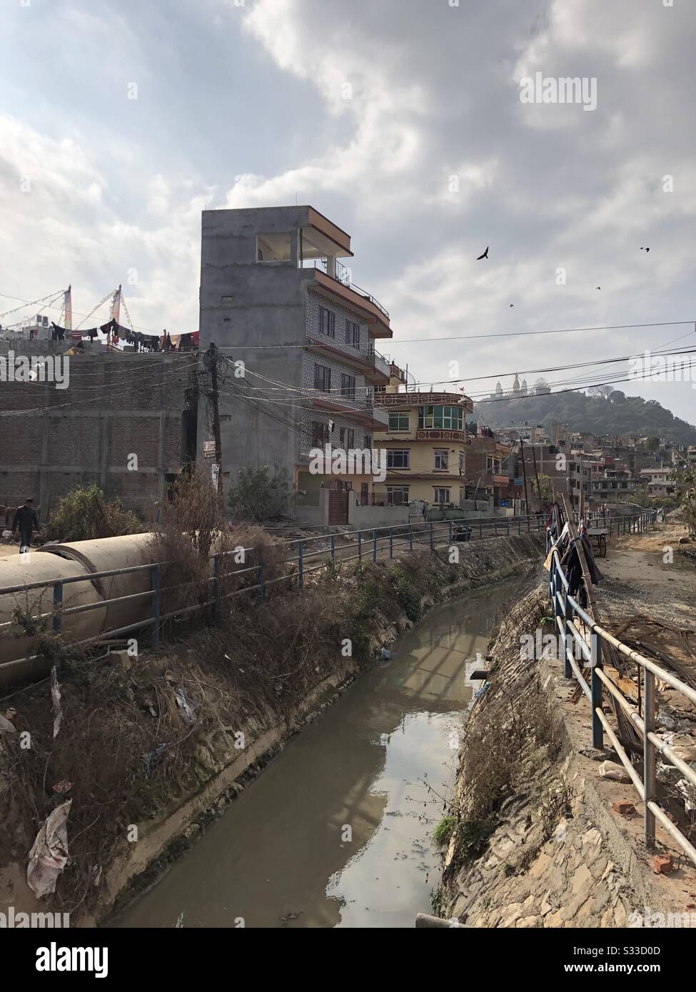 Kleiner Fluss zwischen den hinteren Straßen von Kathmandu an einem sonnigen Wintertag, Nepal. Stockfoto