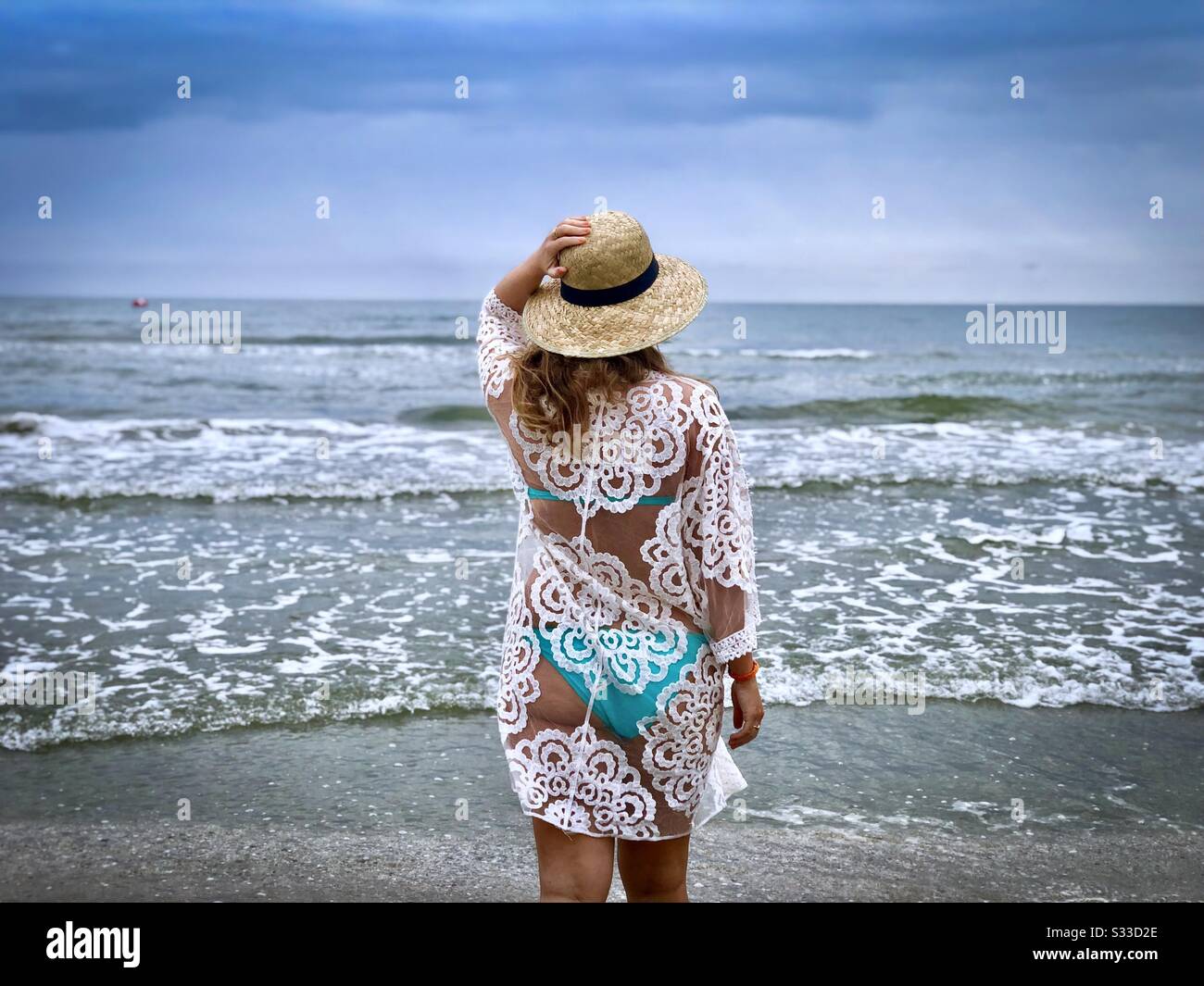 Rücken der Frau, die Bikini am Strand trägt und auf das Meer blickt Stockfoto