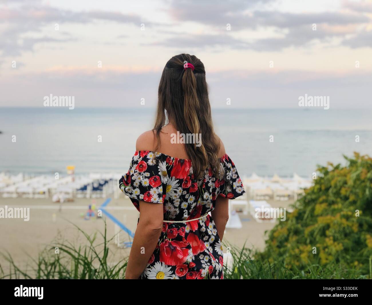 Frau im Sommerkleid mit Blick auf das Meer - Smartphone-aufgenommenes Stockfoto