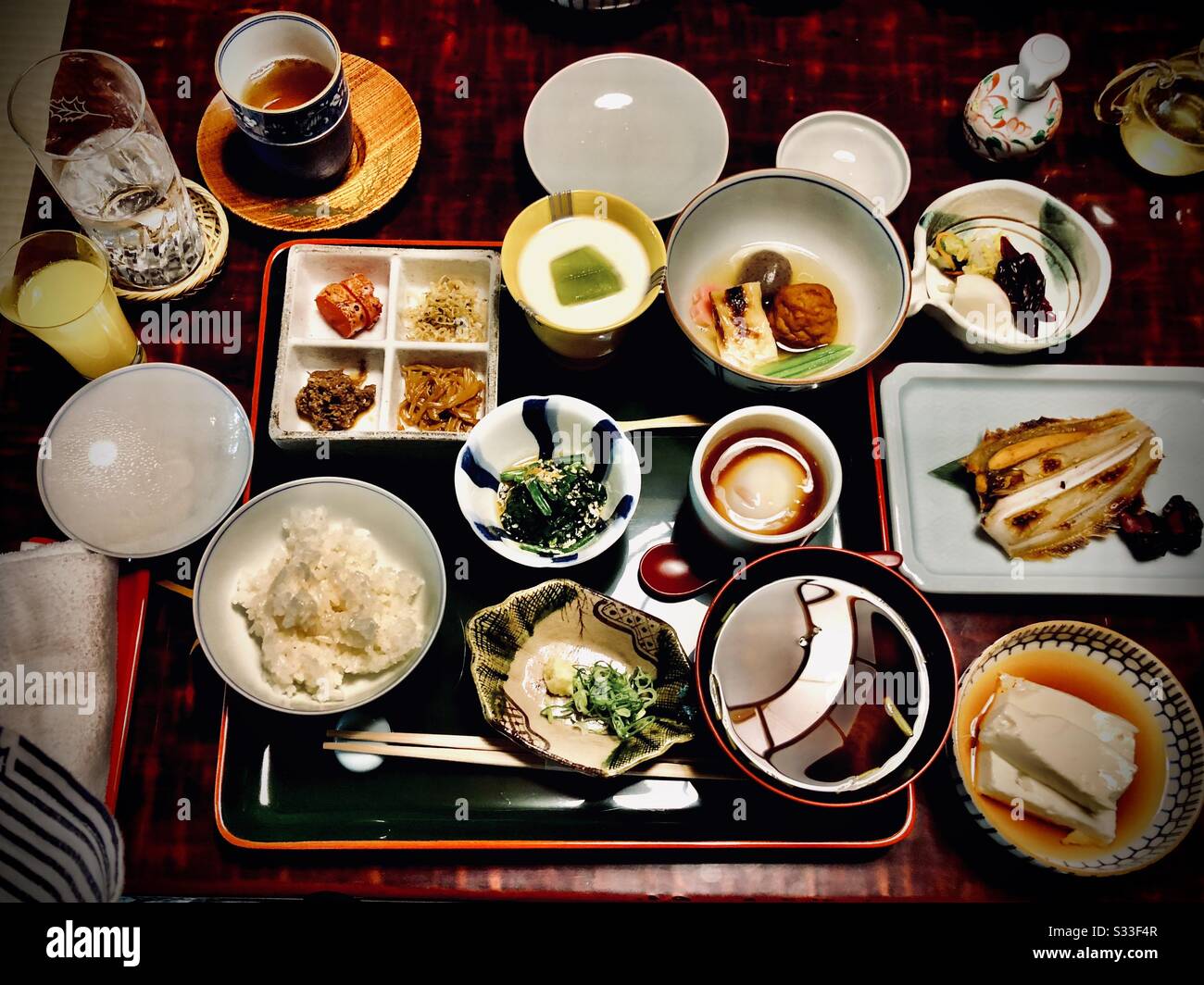Traditionelles japanisches Frühstück in einem Ryokan: Tofu, Reis, rote Miso-Suppe, gegrillter Fisch, Gemüse und Pickles - Smartphone-aufgenommenes Stockfoto