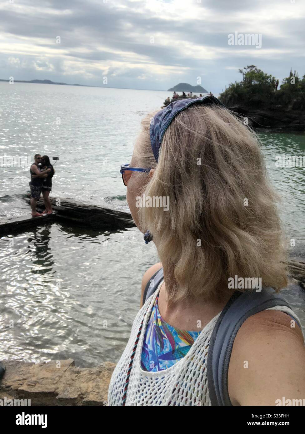 Eine Frau, die auf das Meer blickt. - Smartphone-aufgenommenes Stockfoto