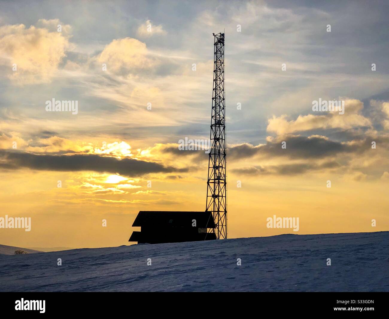 Silhouette von Haus und Sendeturm bei Sonnenuntergang im Winter - Smartphone-aufgenommenes Stockfoto