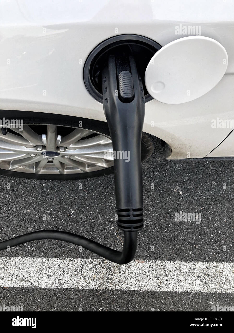 Aufladen von Elektroautos während der Arbeit des Fahrers - Smartphone-aufgenommenes Stockfoto