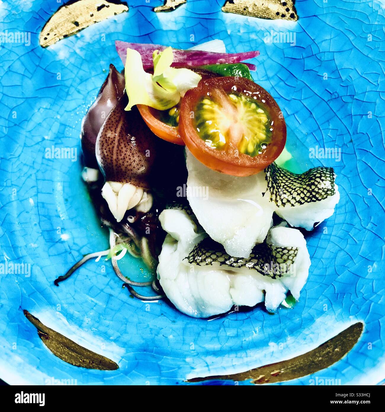 Frischer Fisch und hotaru ika (feuergefirmtes Tintenfisch) auf einer türkisfarbenen, rissigen Porzellanschale mit Goldkintsugi. Kaiseki-Gericht in einem Ryokan in Kyoto, Japan - Smartphone-aufgenommenes Stockfoto