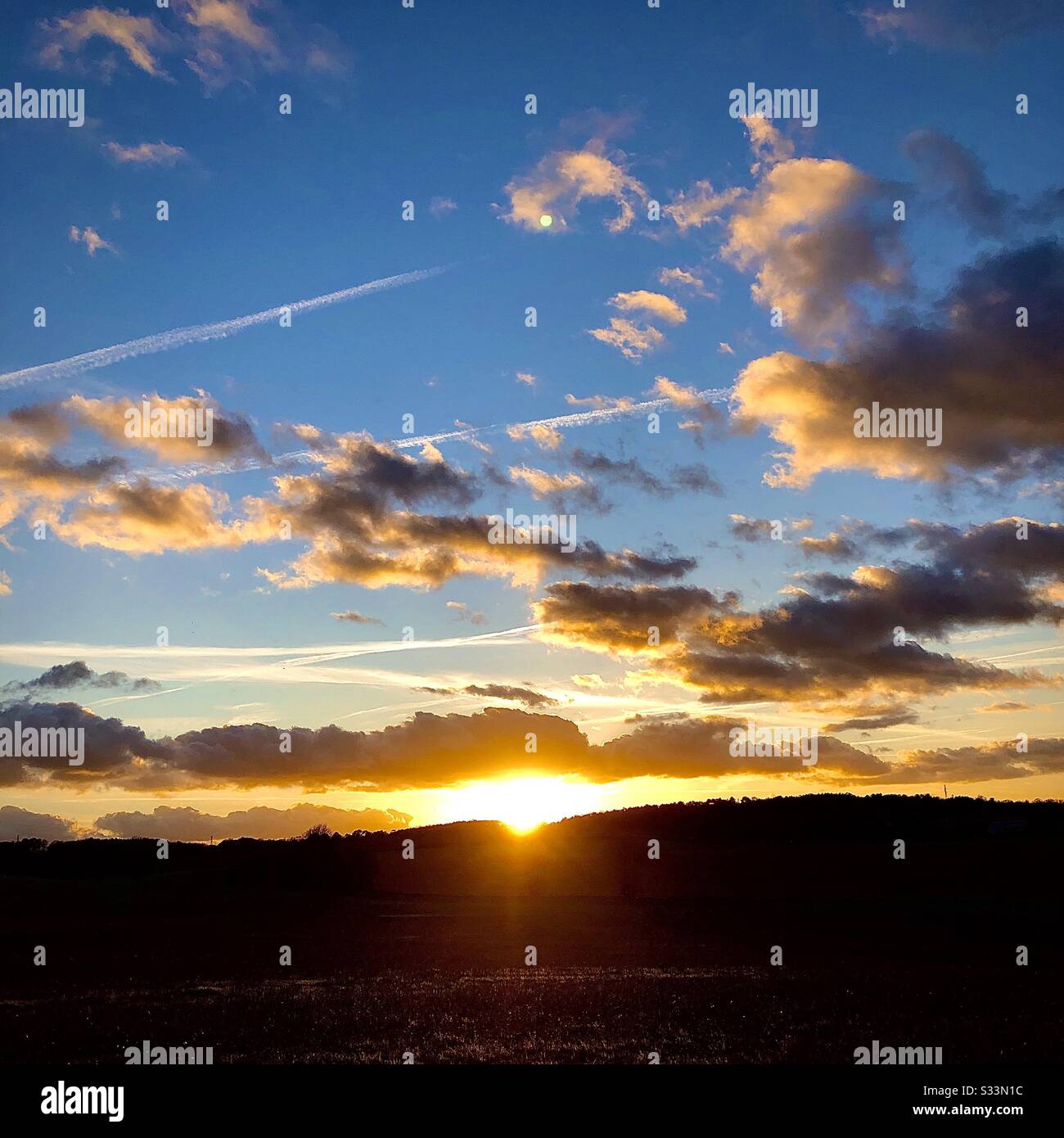 Dramatischer Sonnenuntergang mit goldenem Schein an die Wolken. - Smartphone-aufgenommenes Stockfoto