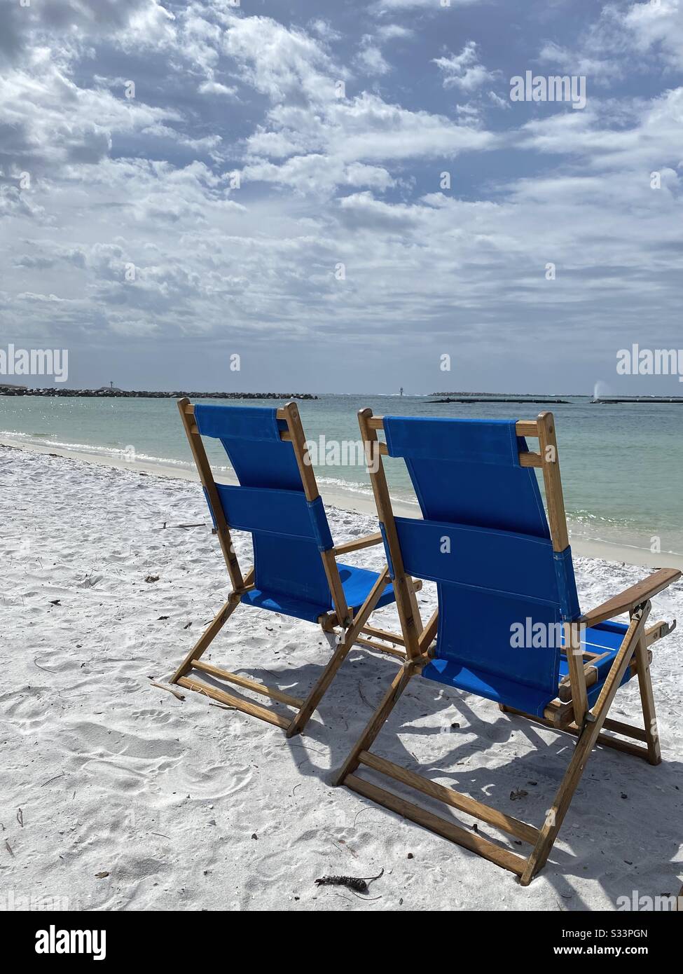 Zwei leuchtend blaue liegen am weißen Sandstrand mit Blick auf das smaragdgrüne Wasser des Golfs von Mexiko - Smartphone-aufgenommenes Stockfoto